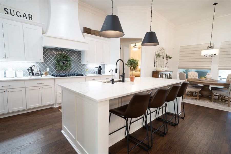 Kitchen with dark hardwood / wood-style flooring, a kitchen island with sink, decorative light fixtures, and custom exhaust hood