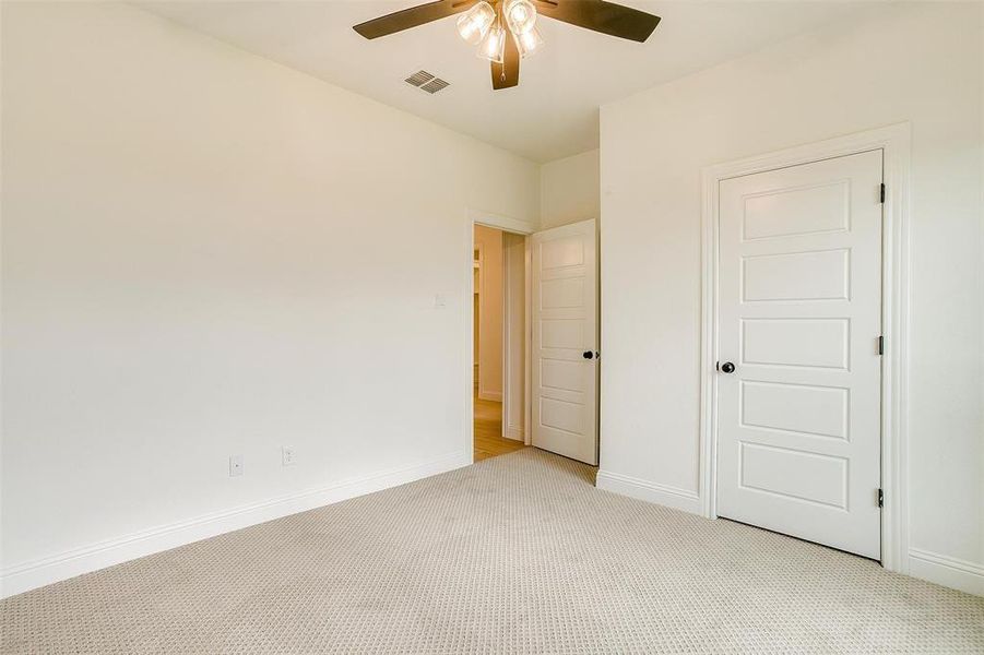 Unfurnished bedroom with light colored carpet and ceiling fan