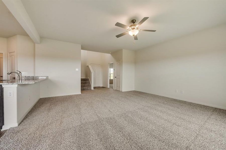 Unfurnished living room featuring sink, carpet flooring, and ceiling fan