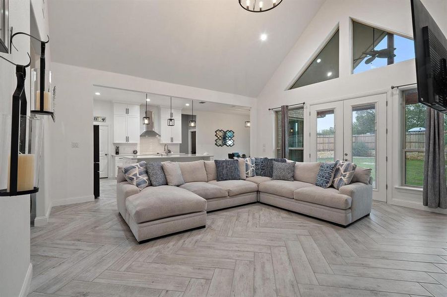 Living room featuring light parquet floors, french doors, and high vaulted ceiling