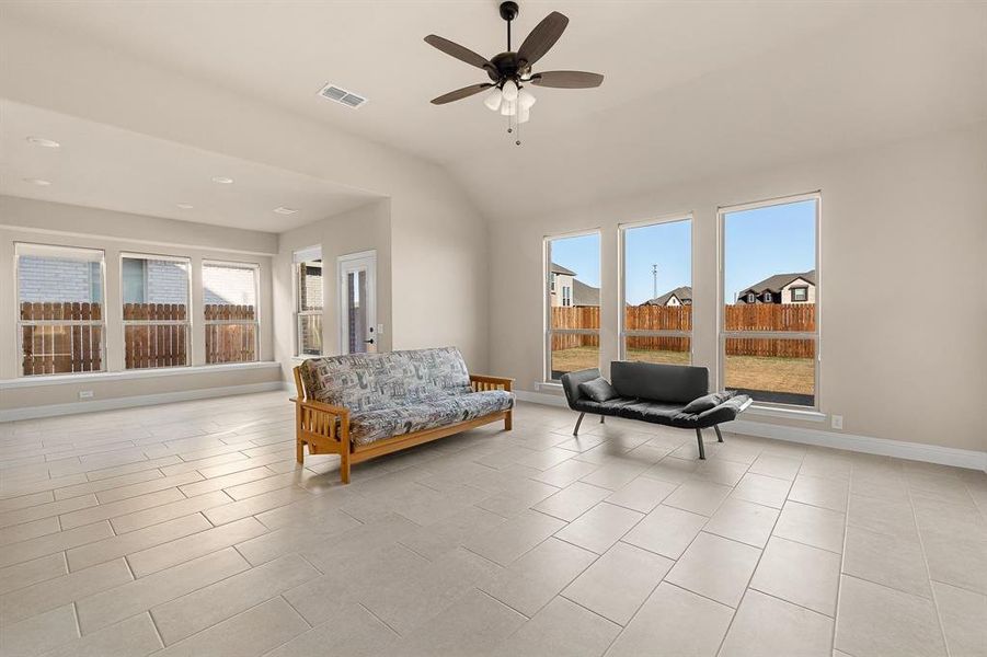 Living area with a wealth of natural light, light tile patterned flooring, and ceiling fan