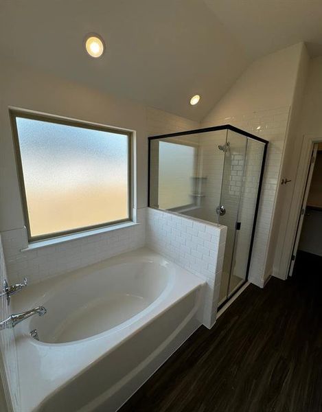 Bathroom with wood-type flooring, lofted ceiling, and plus walk in shower