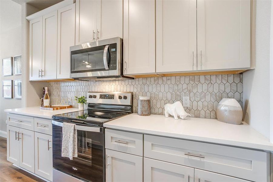 Kitchen featuring white cabinetry, light hardwood / wood-style floors, appliances with stainless steel finishes, and tasteful backsplash