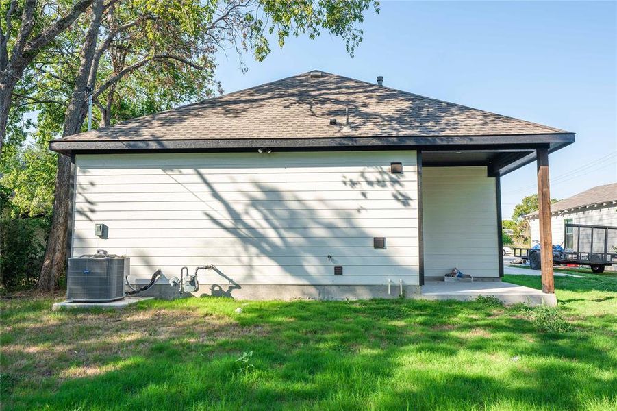 Rear view of property featuring a yard and central air condition unit