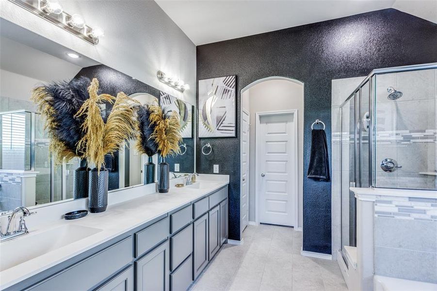 Bathroom featuring tile patterned flooring, a shower with shower door, vaulted ceiling, and vanity