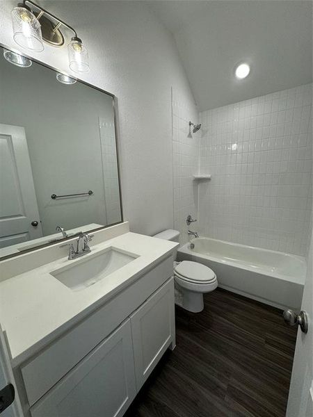 Full bathroom with vanity, tiled shower / bath, hardwood / wood-style floors, and toilet