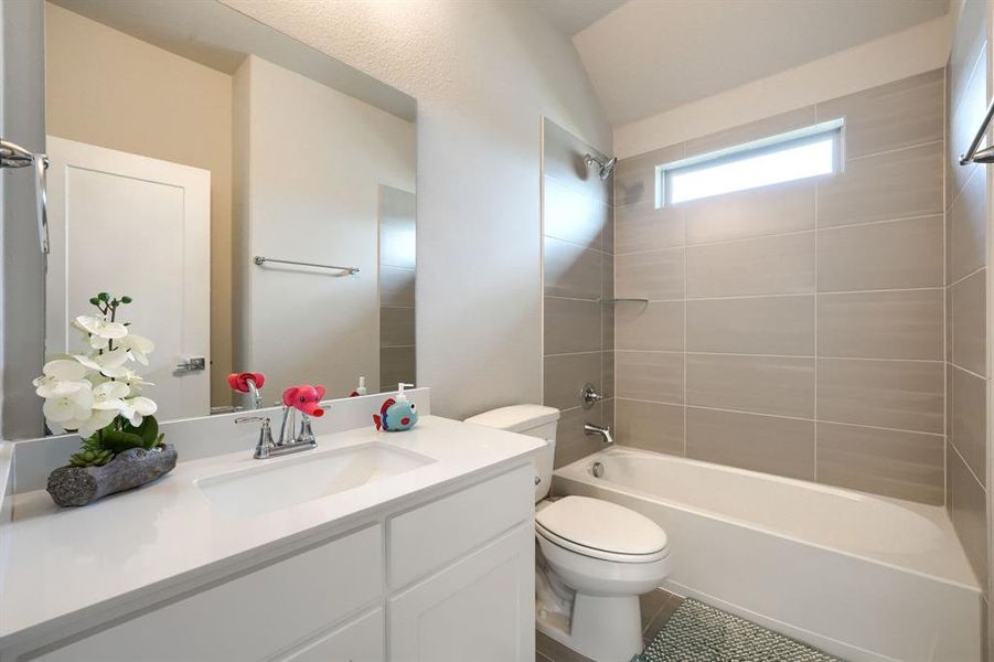 Full bathroom featuring toilet, tile flooring, tiled shower / bath, vanity, and lofted ceiling