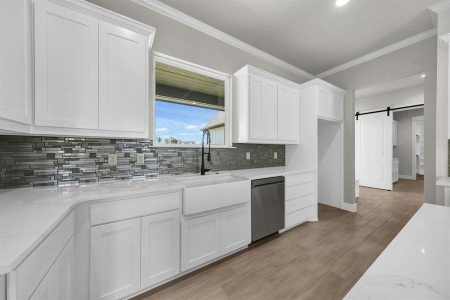 Kitchen with light hardwood / wood-style flooring, tasteful backsplash, large farmhouse sink