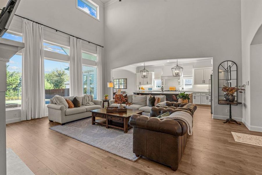 Living room featuring sink, a chandelier, light wood-type flooring, and a high ceiling