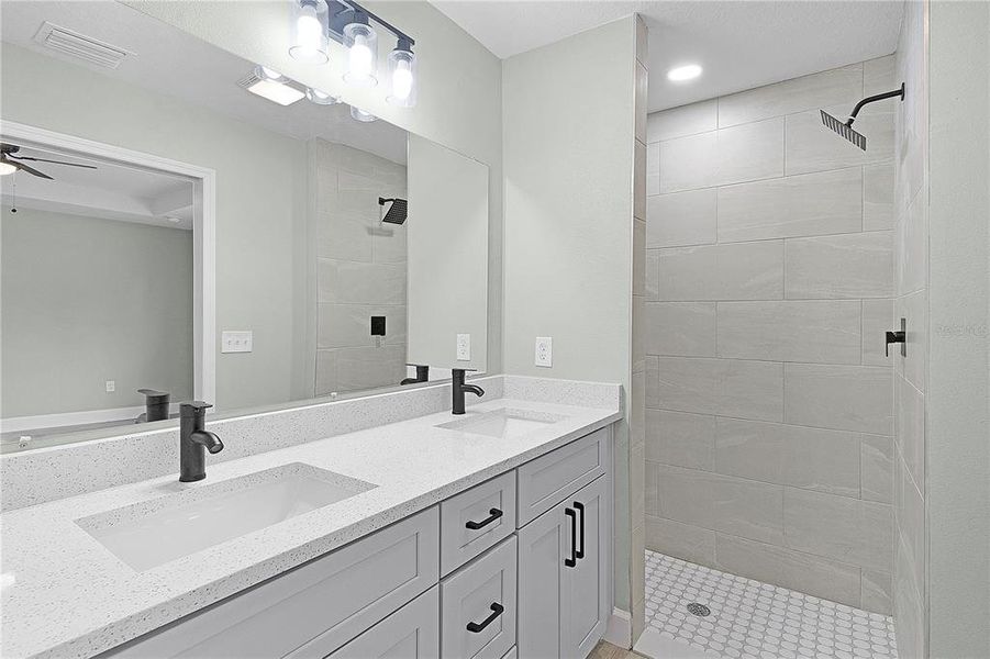 Primary bathroom with double sinks and tiled walk-in shower with rain shower head