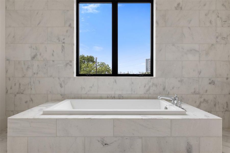 This room benefits from extensive natural light thanks to the large over-tub window. The unobstructed view looks out towards River Oaks and The Galleria skyline.