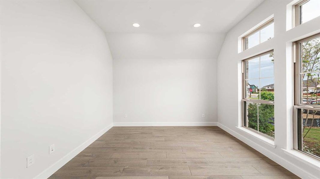 Empty room with lofted ceiling and light hardwood / wood-style floors