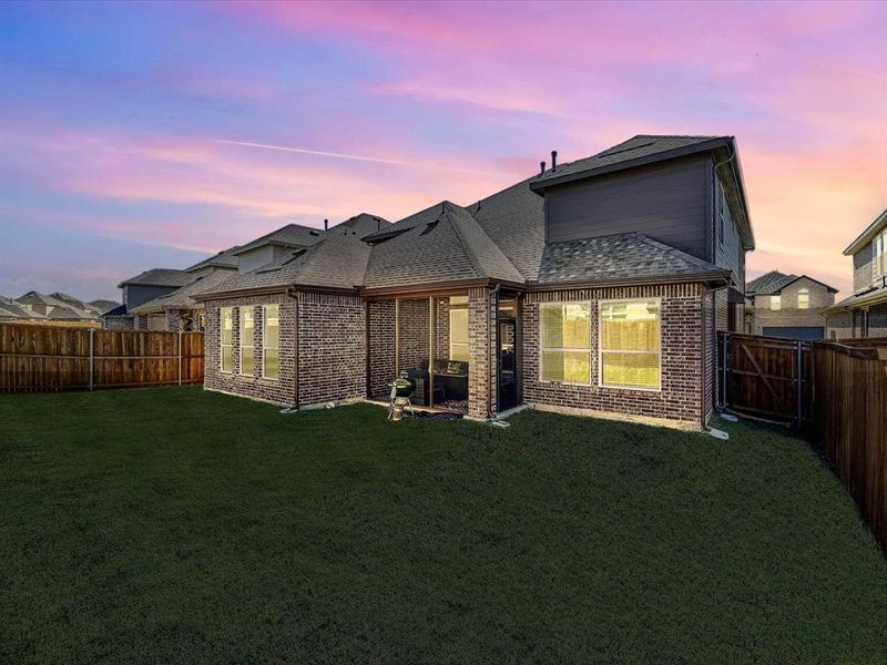 Back house at dusk featuring a lawn