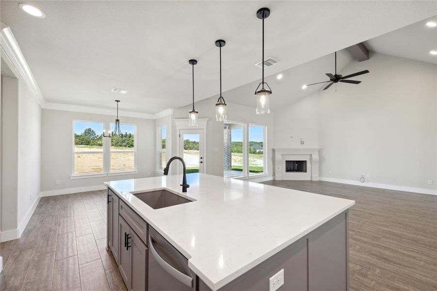 Kitchen featuring ceiling fan with notable chandelier, a center island with sink, decorative light fixtures, and hardwood / wood-style floors