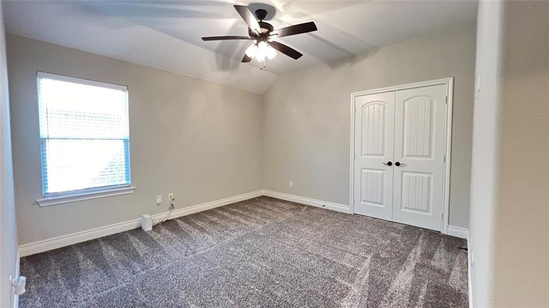 Unfurnished bedroom with lofted ceiling, a closet, carpet, and ceiling fan