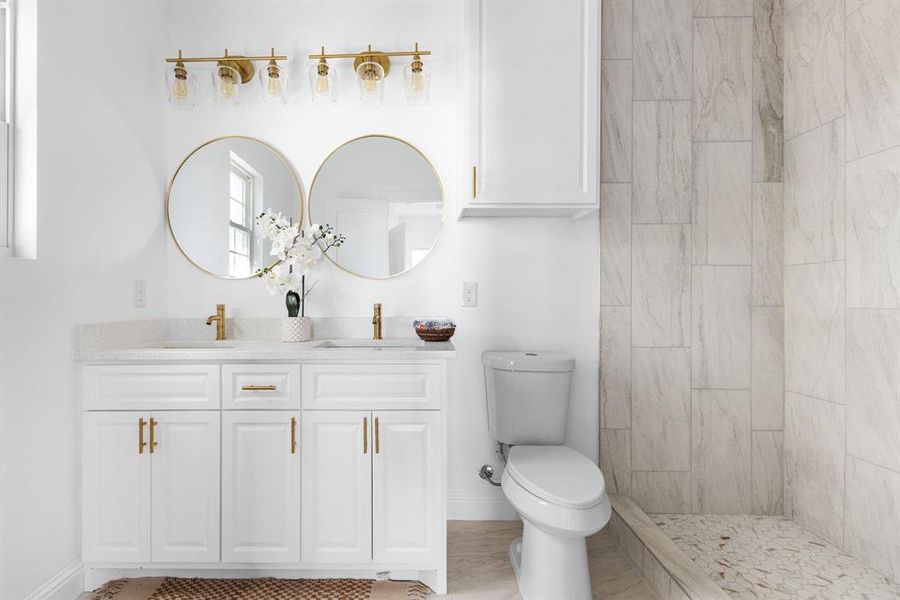 Bathroom with tiled shower, toilet, and vanity