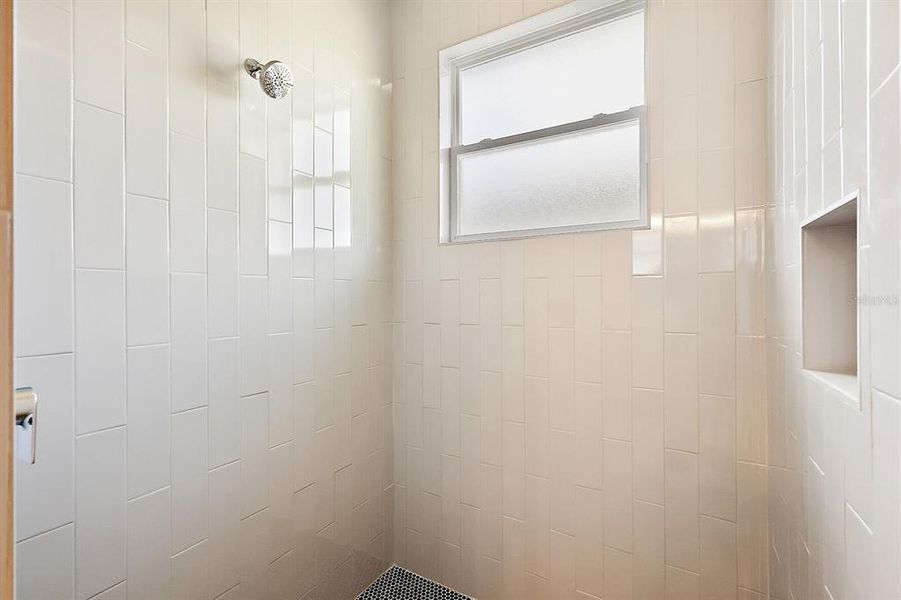 walk in shower with floor to ceiling tile.