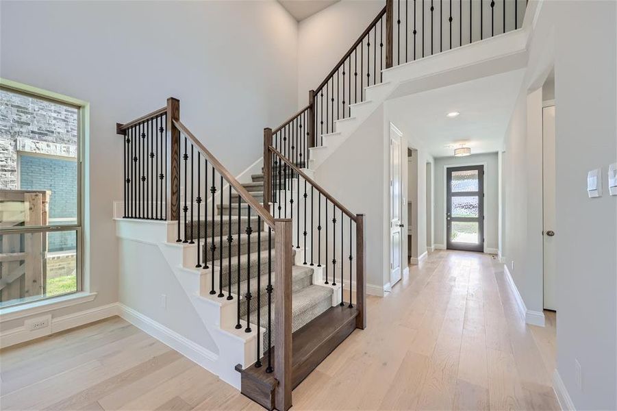 Stairs with light wood-type flooring and a high ceiling