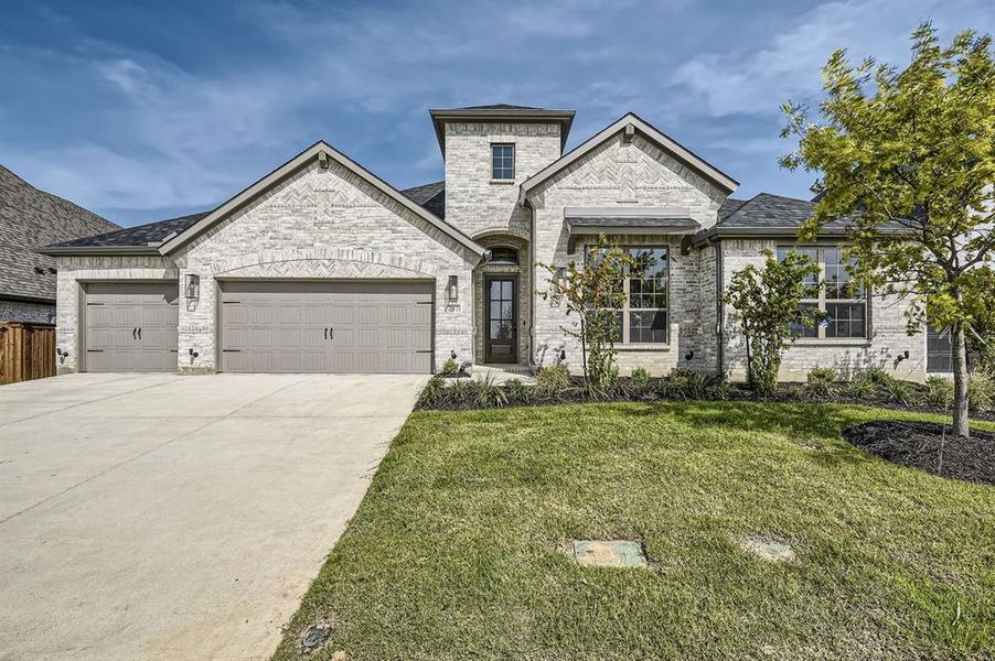 French country home with a garage and a front lawn