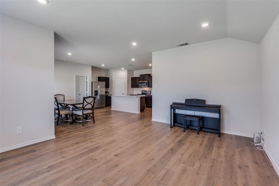 Living room with light hardwood / wood-style flooring and vaulted ceiling