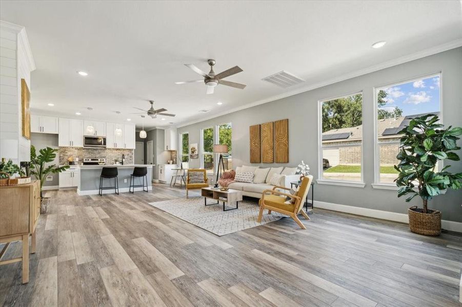 Living room featuring light wood-type flooring, a healthy amount of sunlight, and crown molding