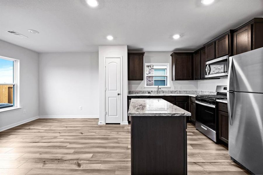 Kitchen with a healthy amount of sunlight, appliances with stainless steel finishes, light hardwood / wood-style flooring, and a kitchen island