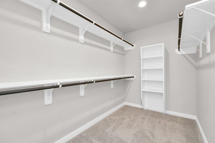 This generously sized closet boasts built-in shelving, providing ample room for organization. With high ceilings and recessed lighting, the ambiance is both bright and welcoming. Plush carpeting underfoot enhances the comfort, while warm paint tones add a touch of coziness.