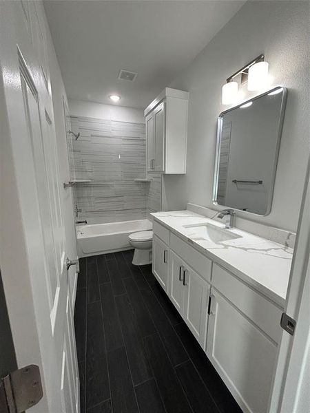 Full bathroom featuring toilet, tiled shower / bath, hardwood / wood-style flooring, and vanity