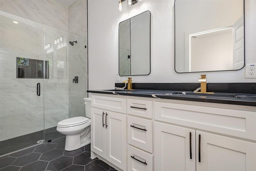 Bathroom with tile patterned floors, a shower with door, vanity, and toilet