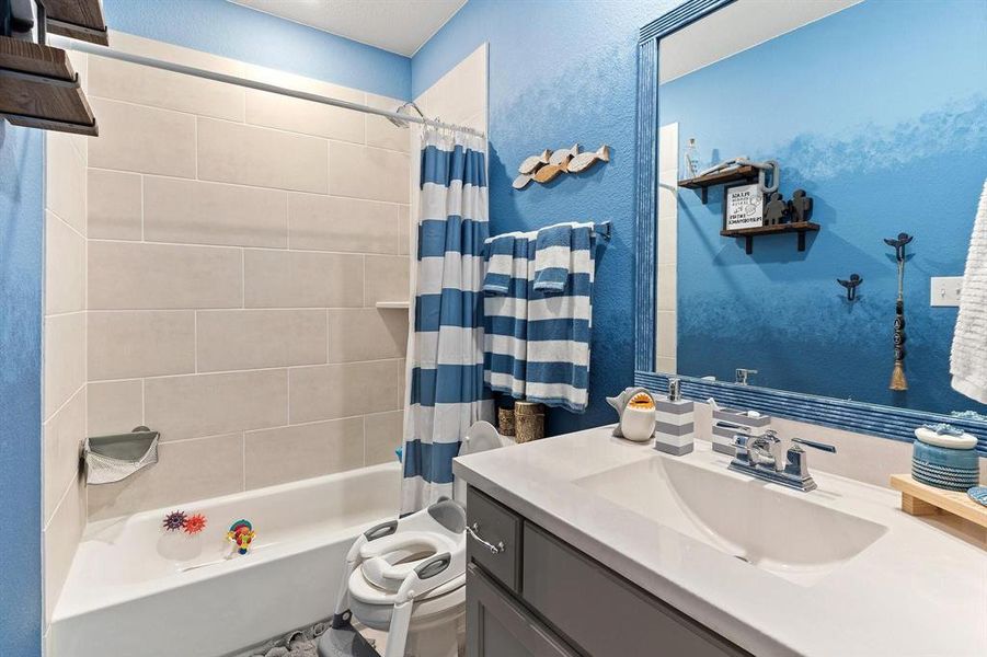 Full bathroom featuring shower / bath combination with curtain, toilet, and vanity