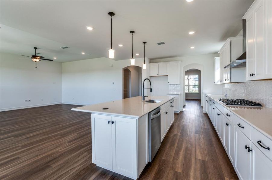 Kitchen featuring sink, an island with sink, dark hardwood / wood-style flooring, hanging light fixtures, and white cabinets