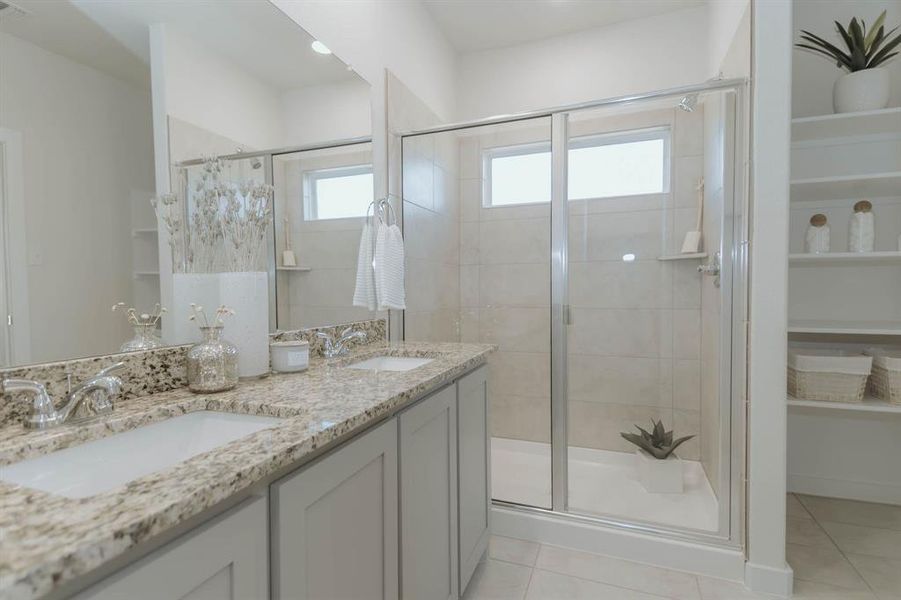 Bathroom featuring vanity, tile patterned flooring, a shower with door, and a healthy amount of sunlight