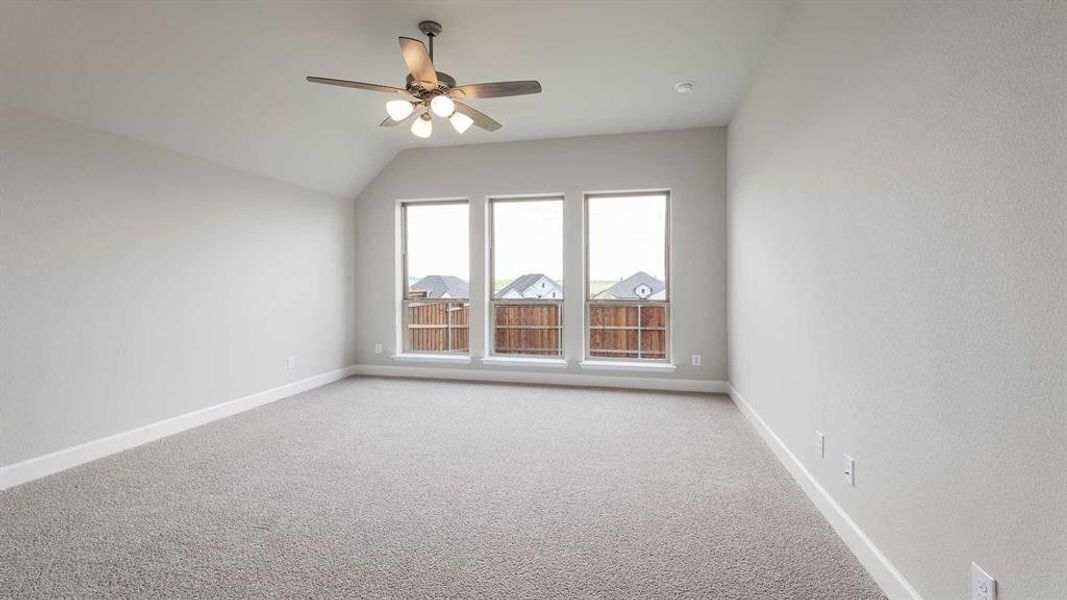 Spare room featuring vaulted ceiling, ceiling fan, and carpet flooring