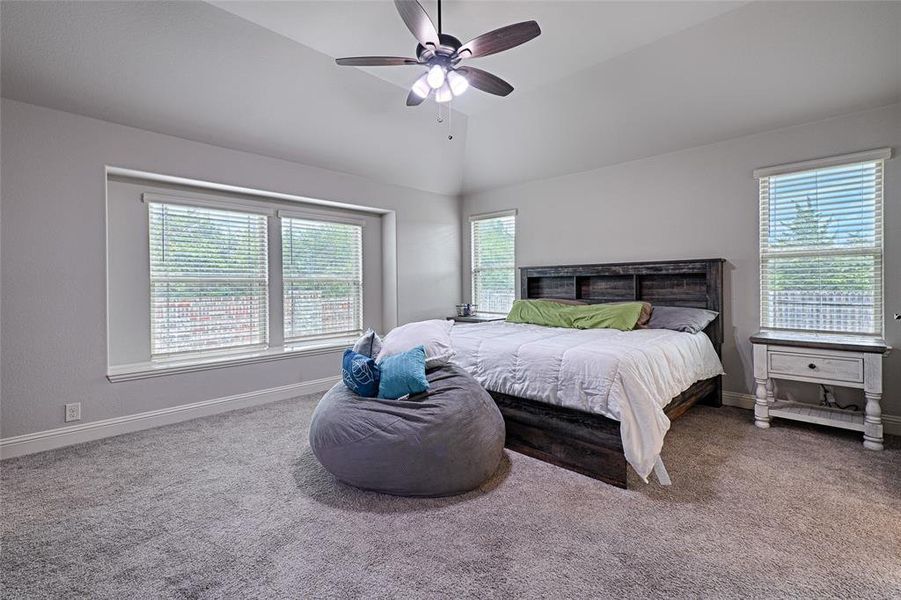 Bedroom featuring vaulted ceiling, carpet flooring, and ceiling fan