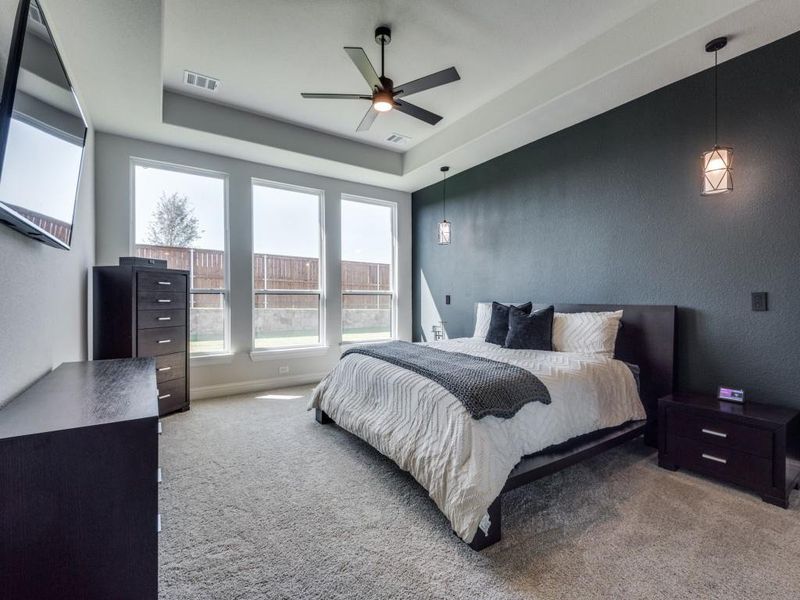 Carpeted bedroom featuring ceiling fan and a tray ceiling