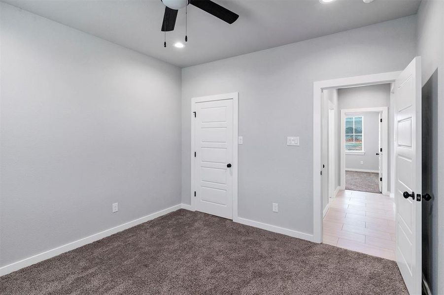 Empty room with ceiling fan and dark colored carpet