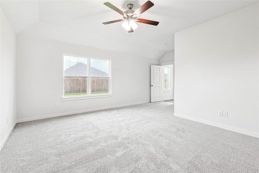 Empty room with light carpet, ceiling fan, and vaulted ceiling