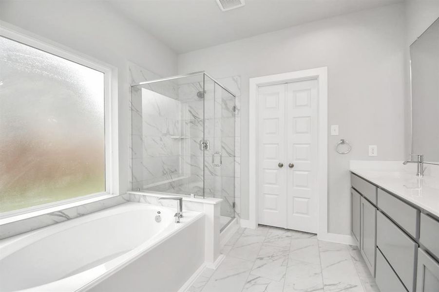 The primary en-suite has a soaking tub to give you that spa experience. The large privacy window allow lots of nature light in the space. Sample photo of completed home with similar floor plan. As-built interior colors and selections may vary.