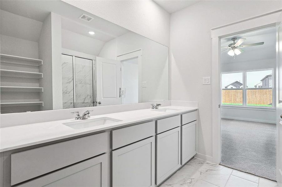 Bathroom featuring ceiling fan, a shower with door, tile patterned floors, and vanity