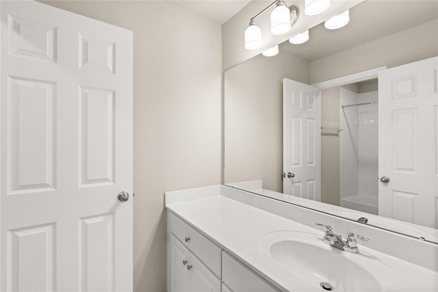 The secondary bath features tile flooring, white cabinetry and light countertops and a shower/tub combo. Perfect for accommodating any visiting family and friends.