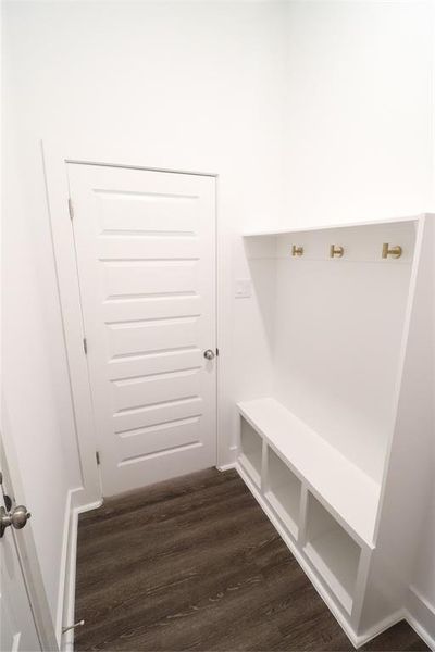 Oversized mud room located next to garage with brushed gold coat hooks and bult-in shoe storage as an upgrade.