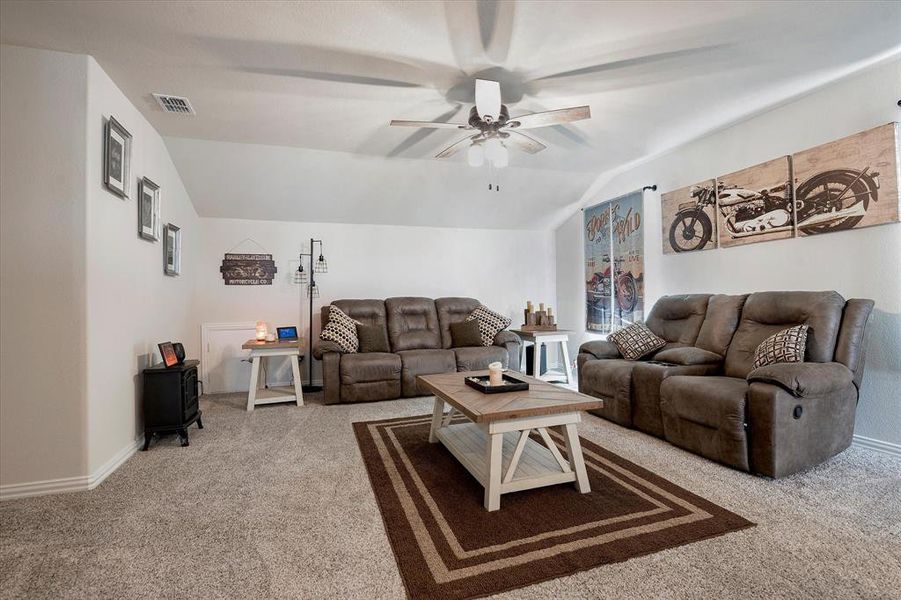 Carpeted living room featuring ceiling fan and lofted ceiling