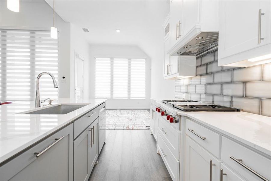 Kitchen featuring sink, hardwood / wood-style floors, backsplash, and white cabinetry