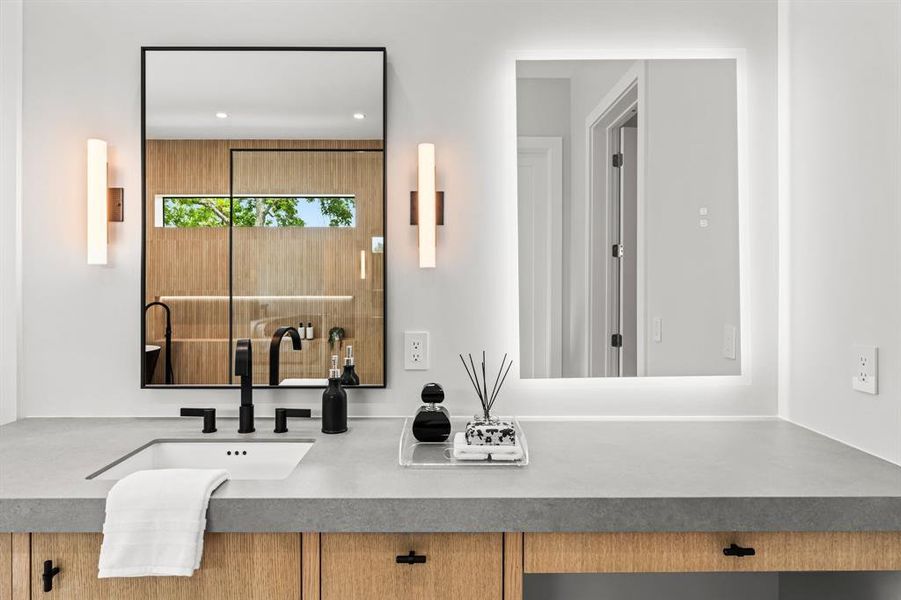 Separate vanity each spaces adorned with leather textured grey porcelain countertops.