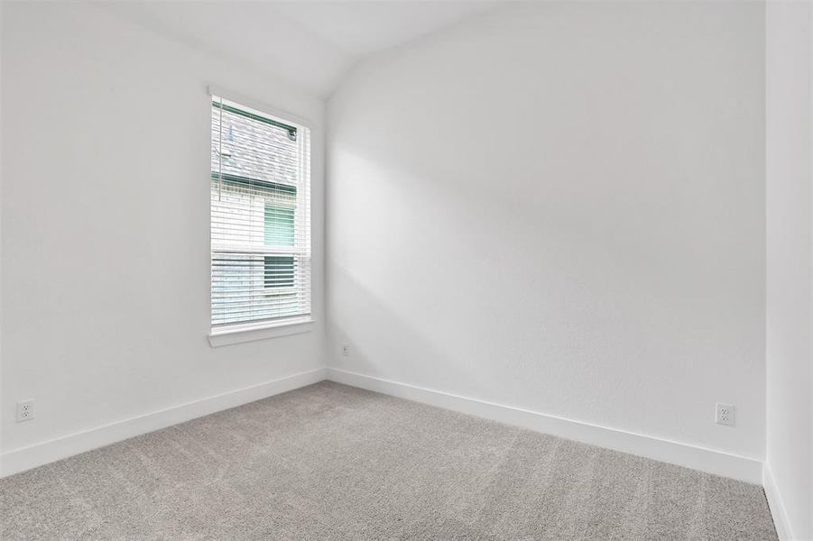 Carpeted empty room featuring vaulted ceiling