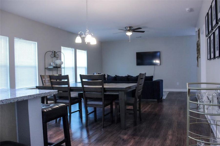 Dining space featuring ceiling fan with notable chandelier and dark hardwood / wood-style flooring