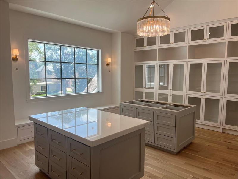 Primary closet with two islands, custom lighting and white oak floors.