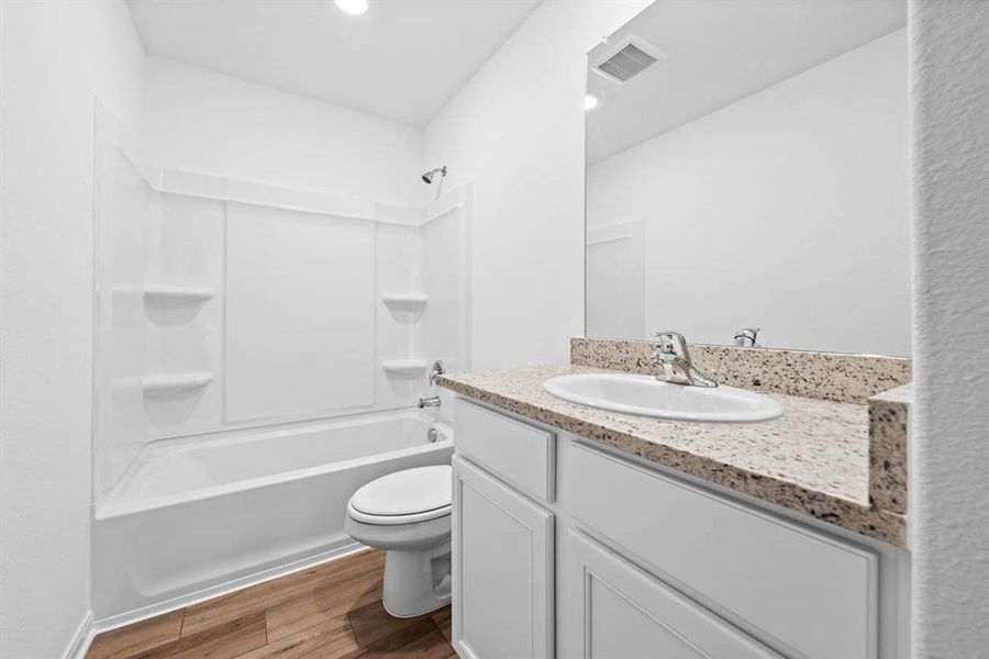 Secondary bathroom includes granite counters, designer white cabinetry and luxury vinyl plank flooring.