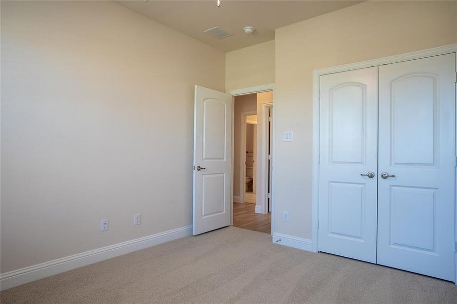 Unfurnished bedroom featuring light carpet and a closet