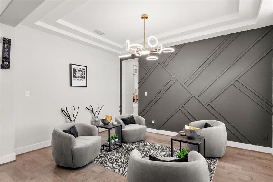 The extra living room or formal dining room features elegant tray ceilings, a sophisticated gray accent wall, and a modern chandelier, creating a stylish and inviting ambiance.